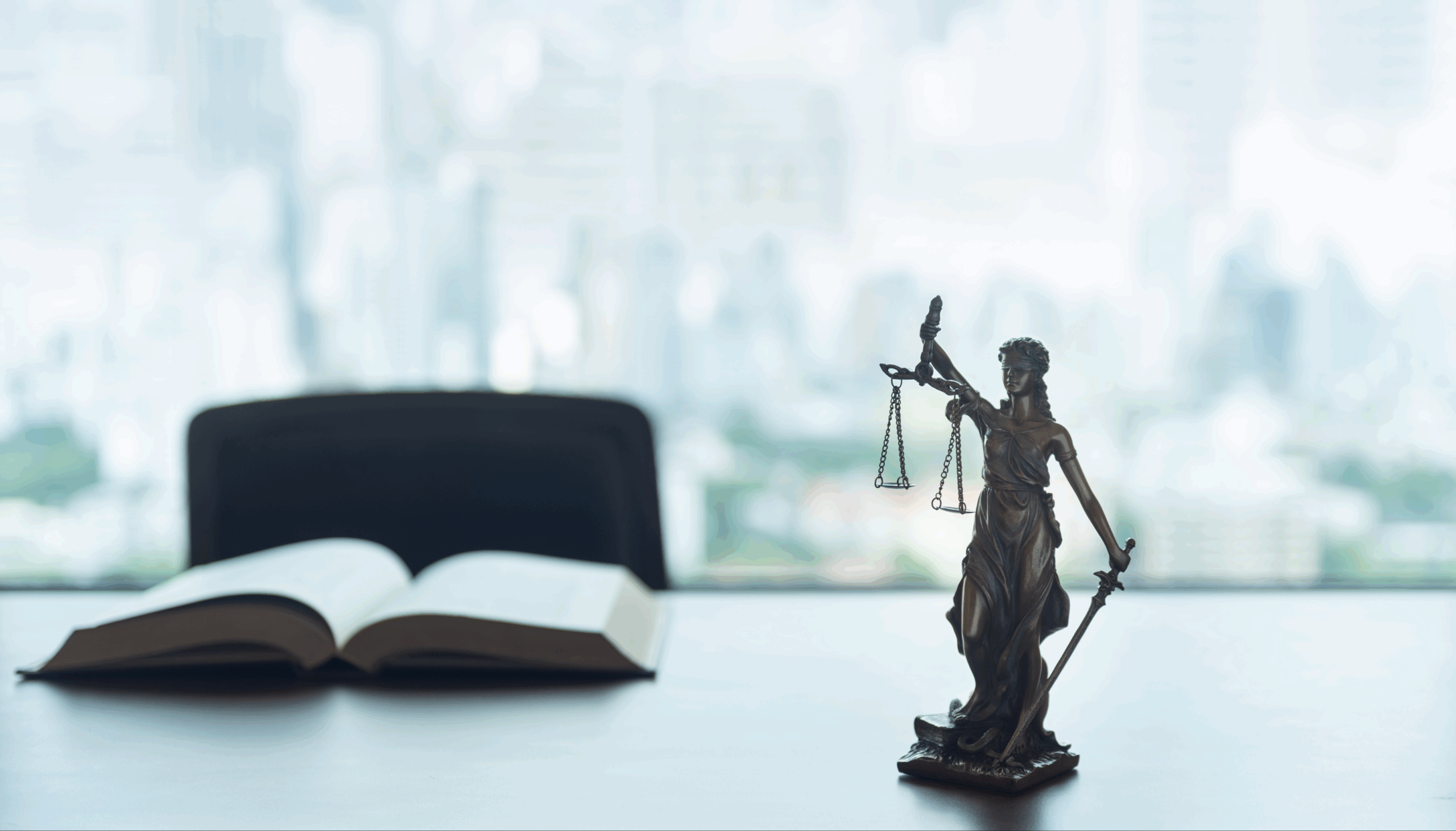 Lady Justice statue and open law book in modern law office