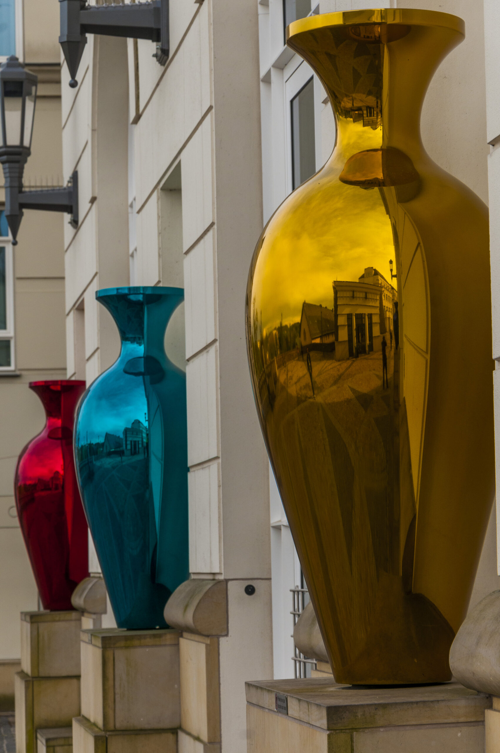 Reflection of Luxembourg’s Cité Judiciaire in gold, blue, and red vase sculptures