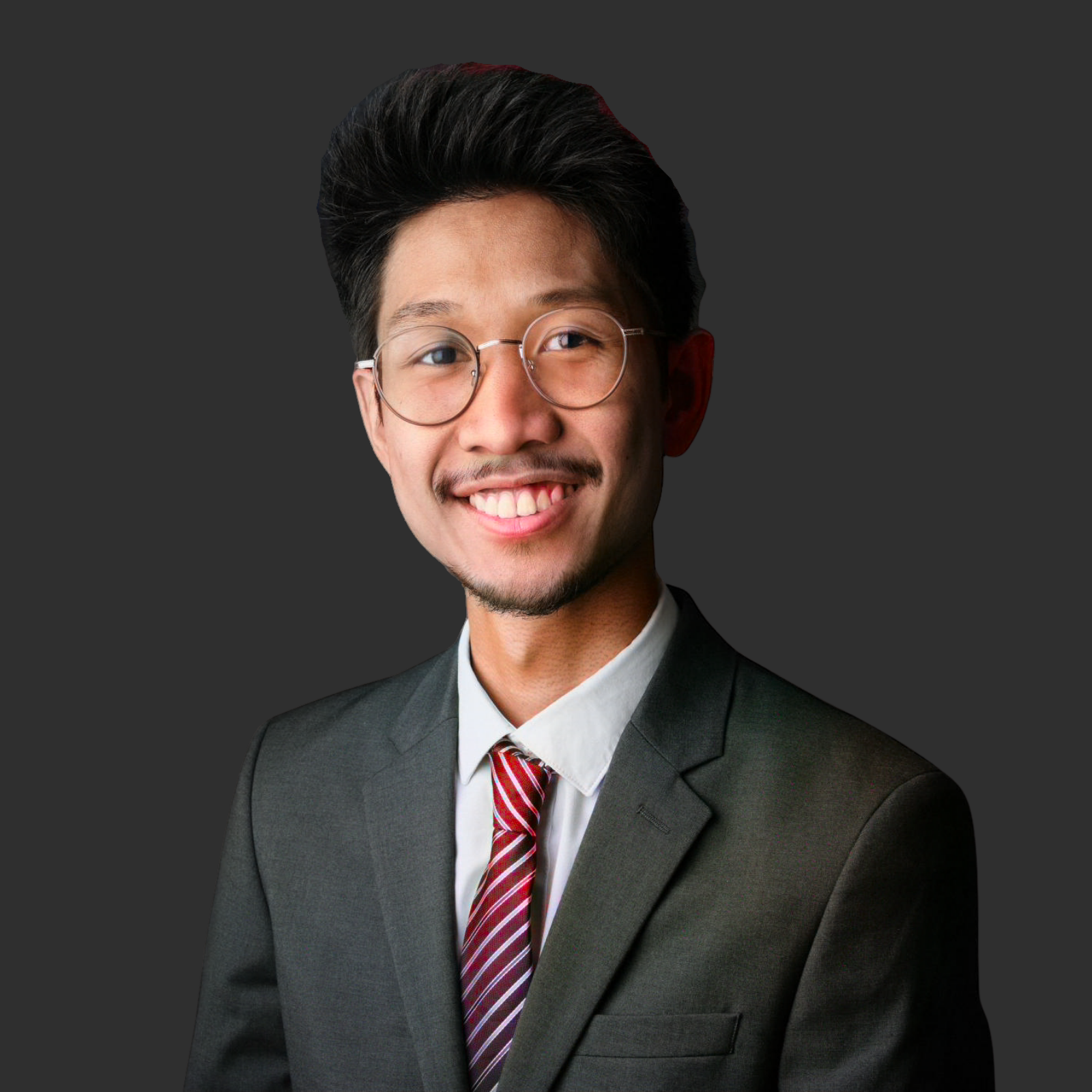 Porträt von Chatuphon Hasuk, Financial Support Officer bei JBV&Partners Luxembourg, im Anzug, vor grauem Hintergrund stehend, leicht lächelnd, spezialisiert auf Buchhaltung und Finanzmanagement